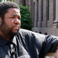 A BIPOC man sitting outside