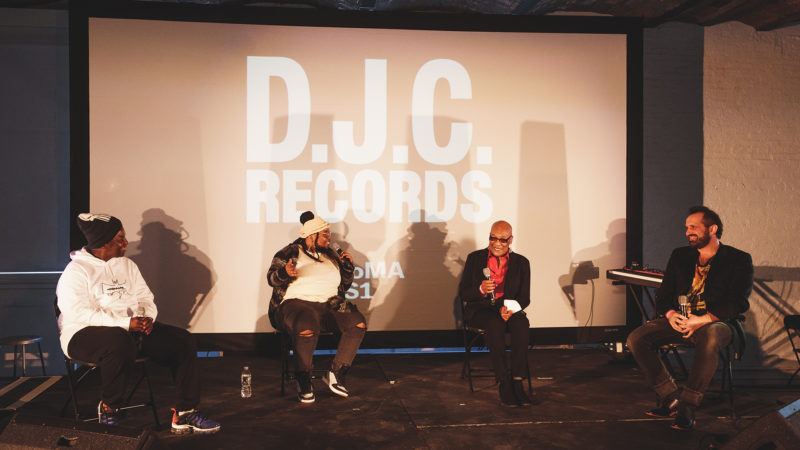 Four people sit on a stage and have a public discussion.