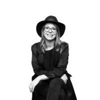 A British woman posing in black and white wearing a hat and glasses