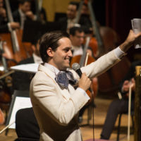 A Latinx man waving from the orchestra stage