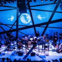 Large instrumental ensemble performing in a venue with dark blue lights