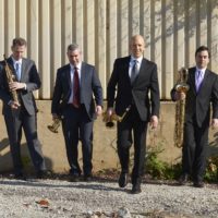 Four caucasian men holding different saxophones