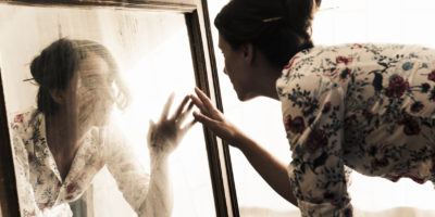 Artist mid adult woman looking herself on mirror. Dusts and dirts on the mirror...