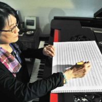 An AAPI woamn sitting in front of manuscript paper