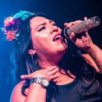 Stephanie Bergara on stage singing with a microphone. (Photo by Jake Rabin)