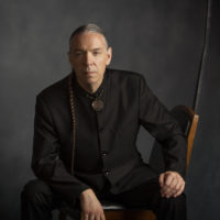 A Chickasaw man sitting with a dark background