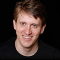 A Caucasian man posing against a black background