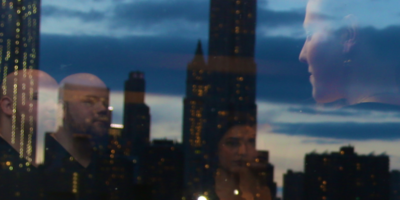 A photo of the staff members of Creatives Care shown reflected in the window of a high rise building foregrounding the Manhattan skyline.